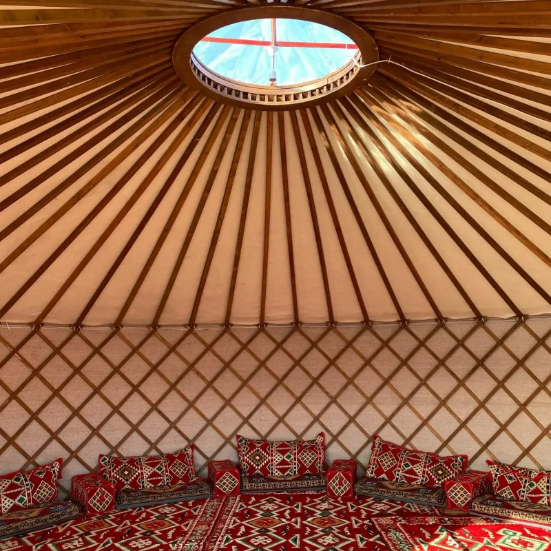 pexels-photo-13841007-13841007 An inviting yurt interior with vibrant red patterns and ceiling view.